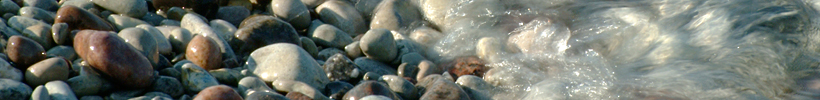 Närbild på stenstrand med inrullande våg